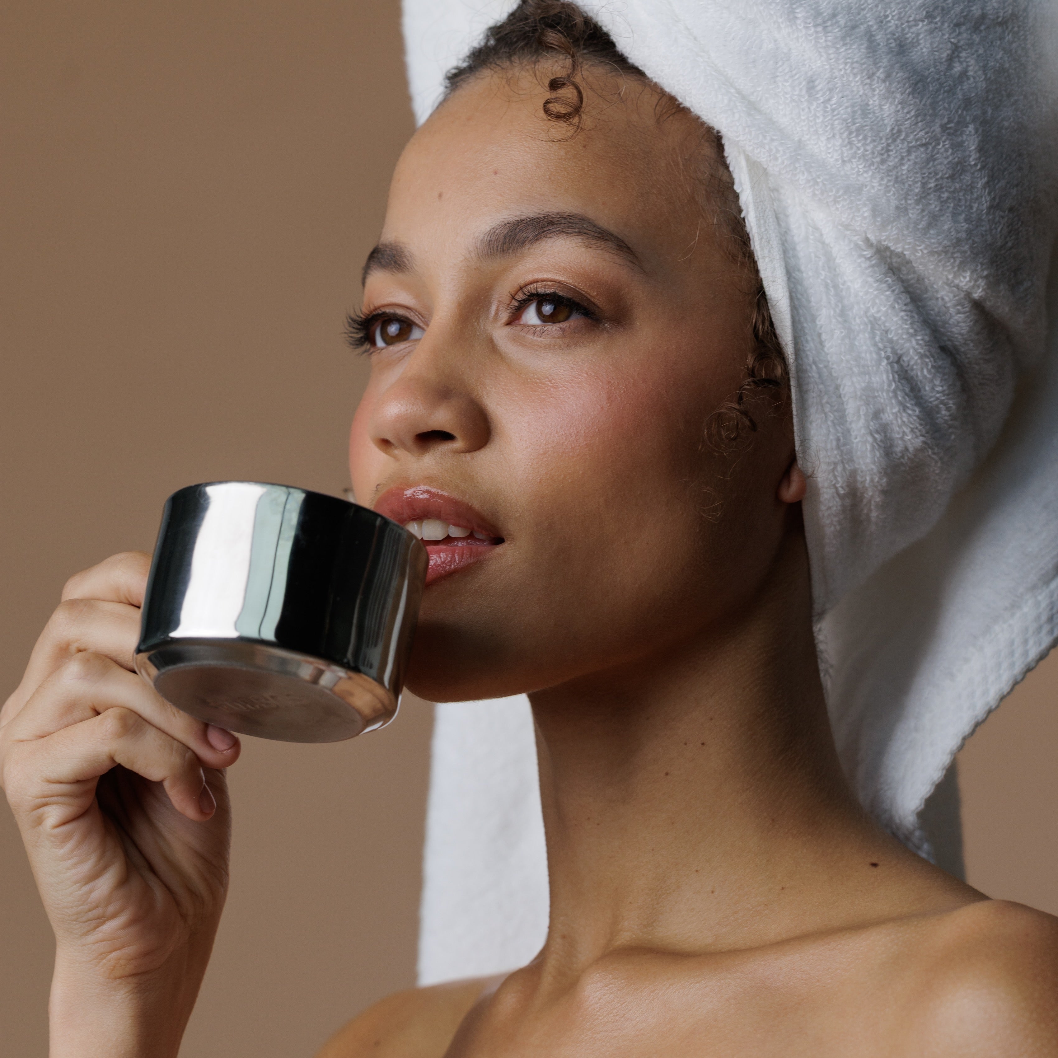 Woman drinking refreshing tea with a towel over her hair
