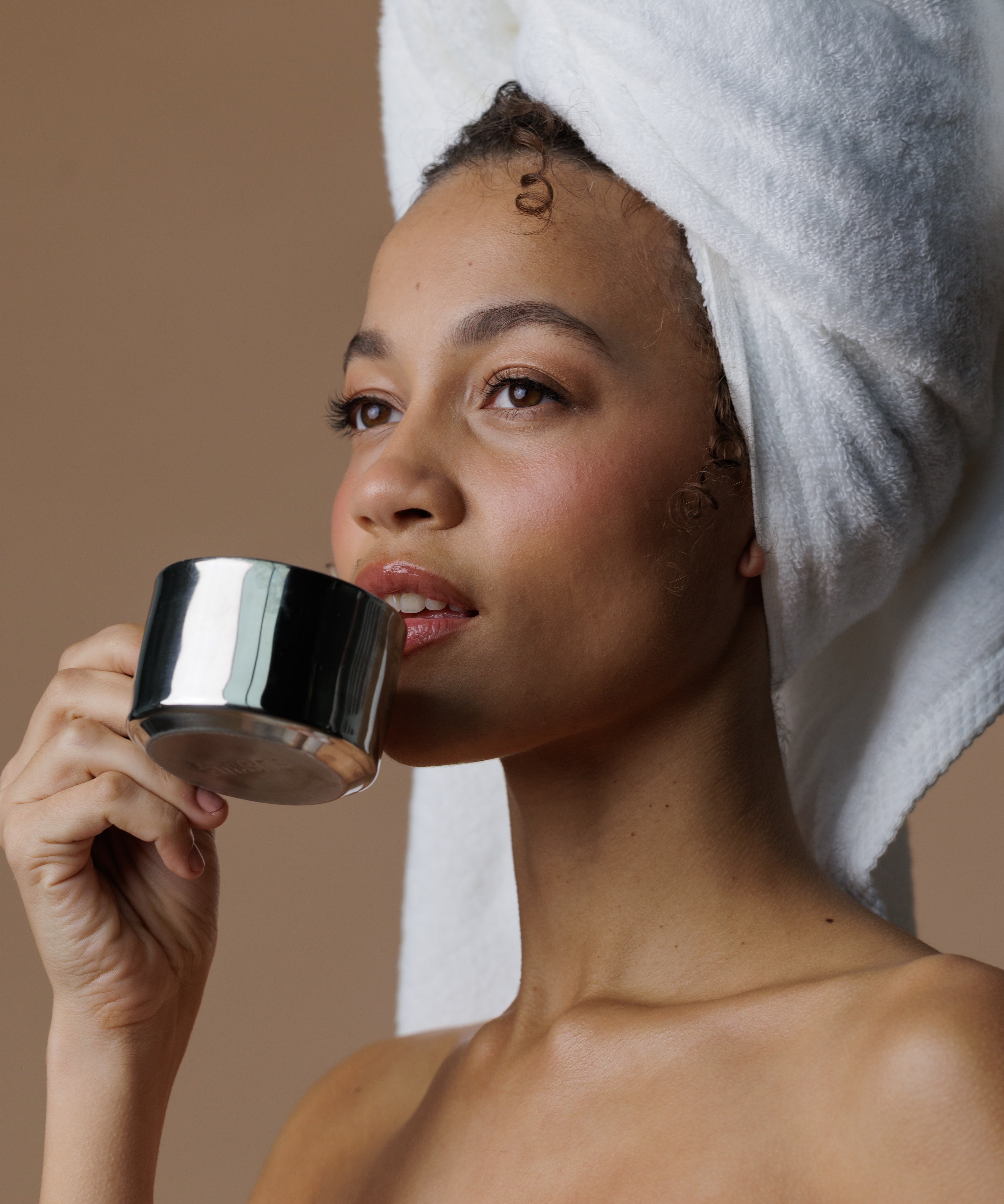 Woman drinking refreshing tea with a towel over her hair