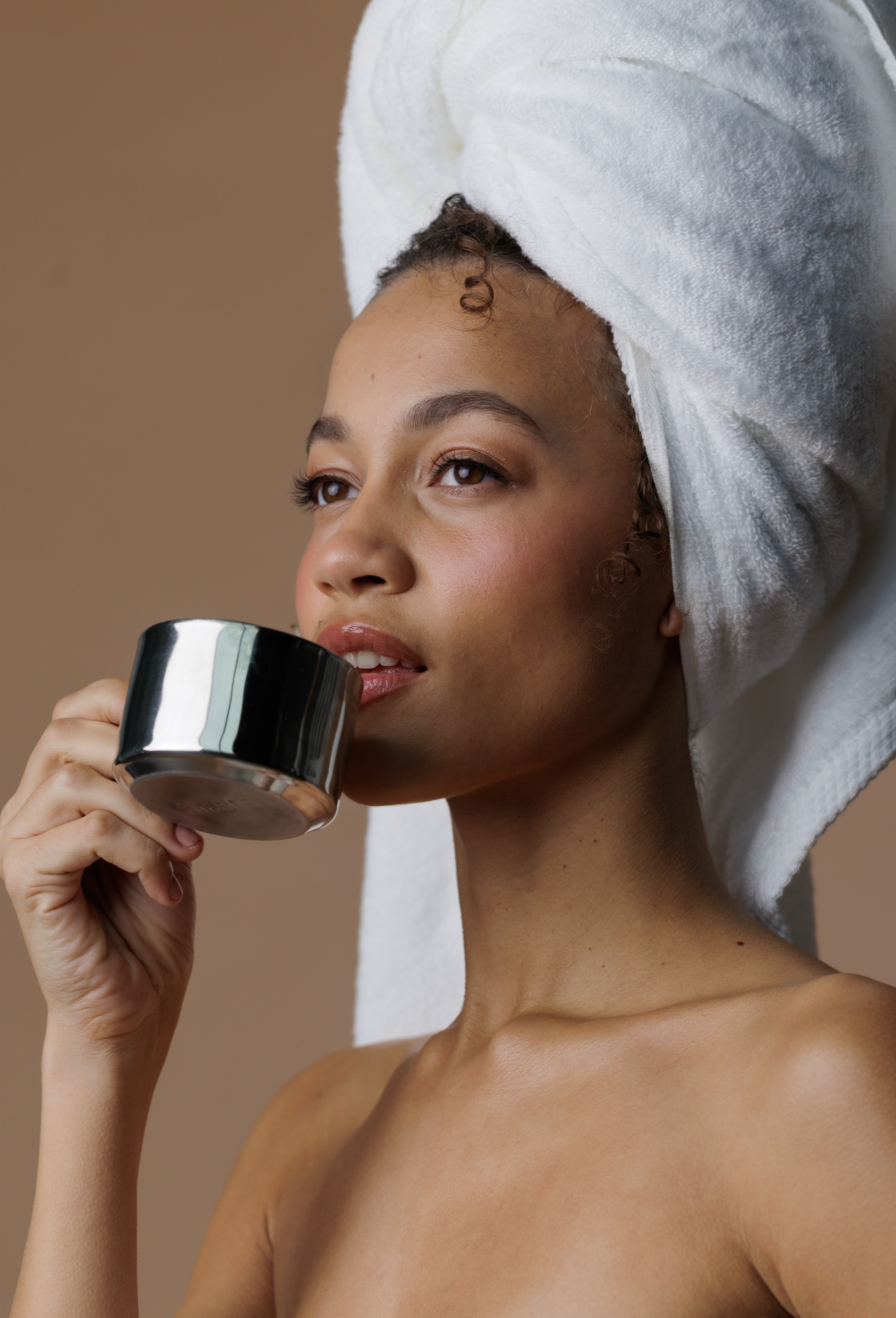 Woman drinking refreshing tea with a towel over her hair