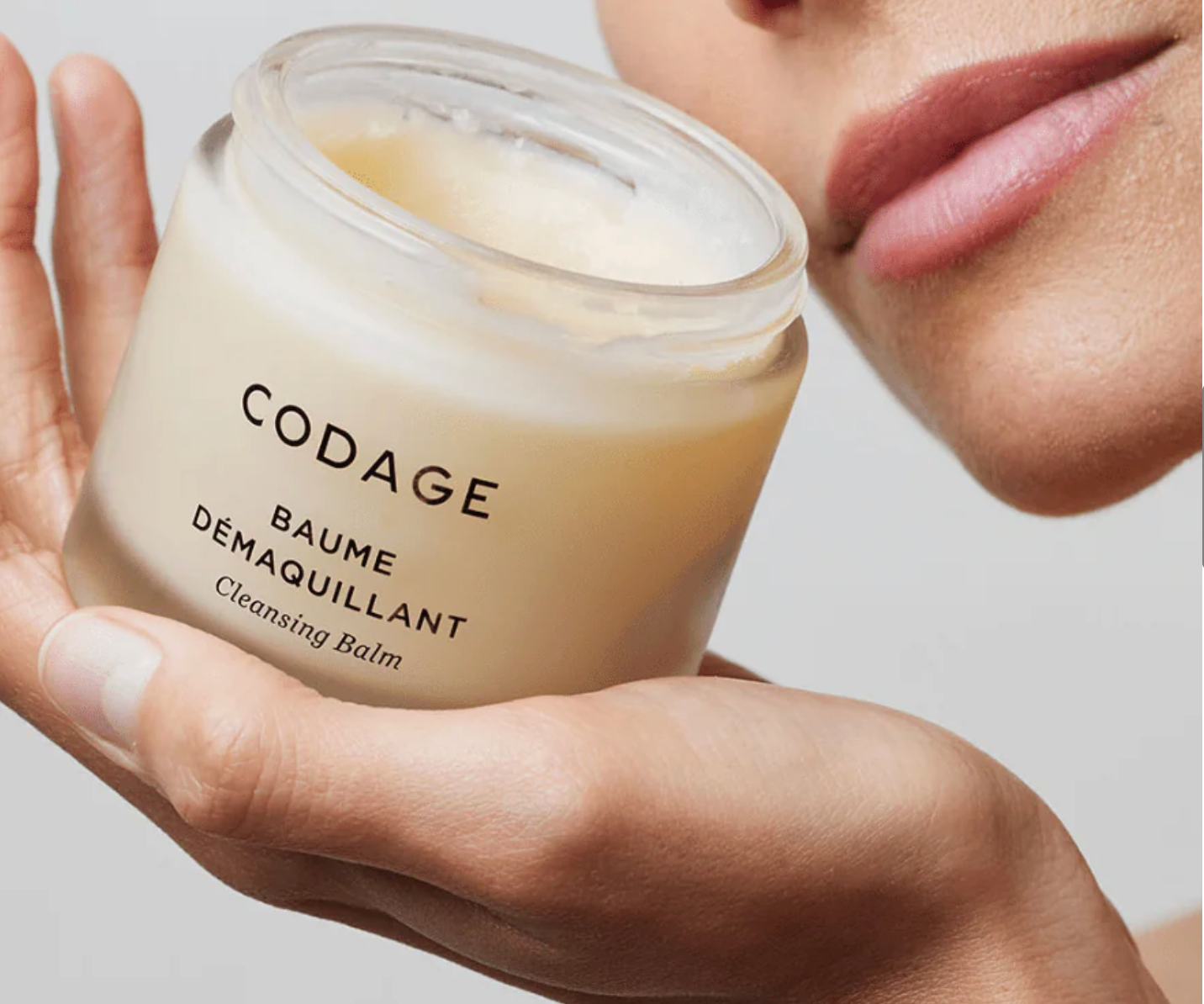 Person holding a jar of Codage cleansing balm with a neutral background