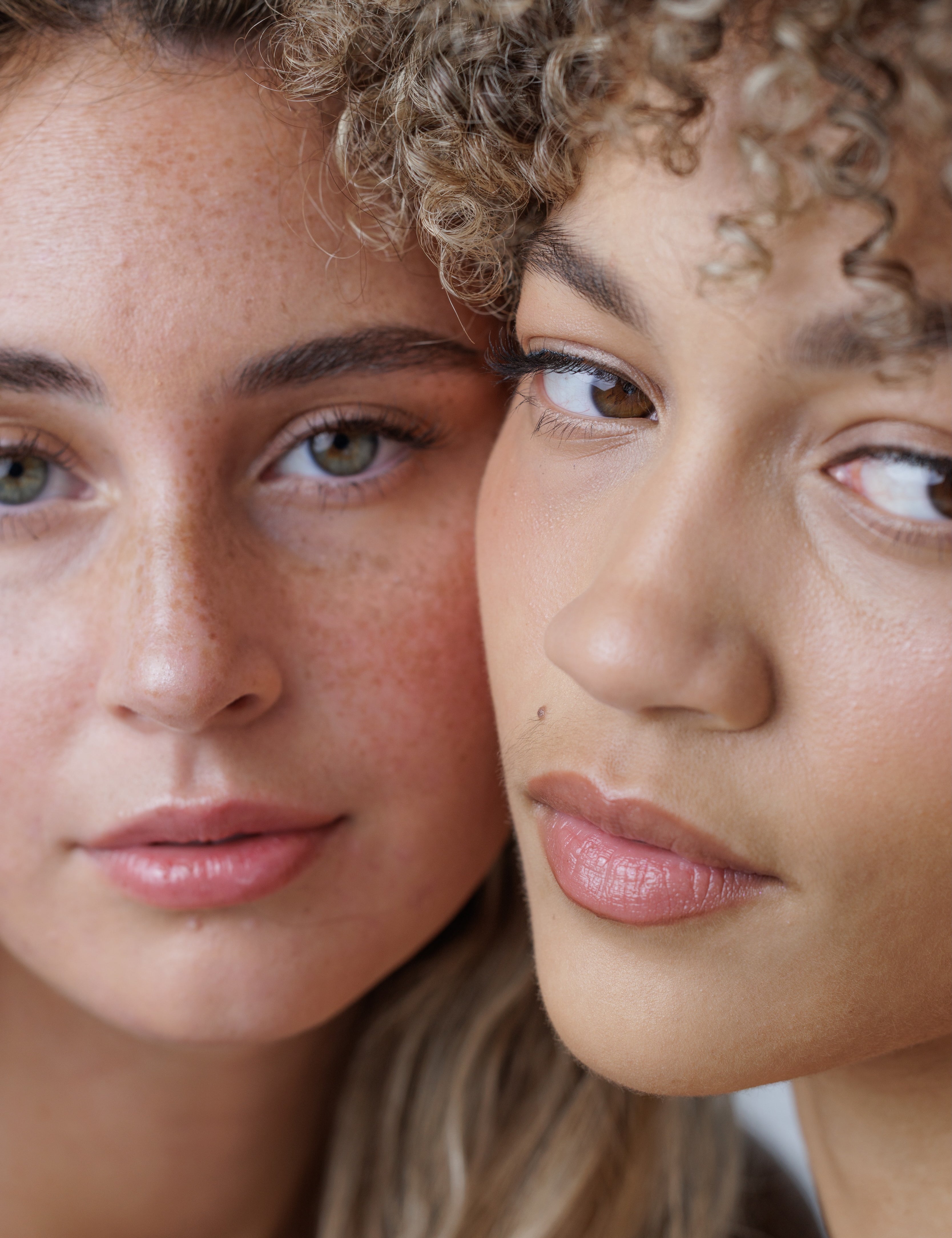 Close-up of two women with curly hair looking at each other.