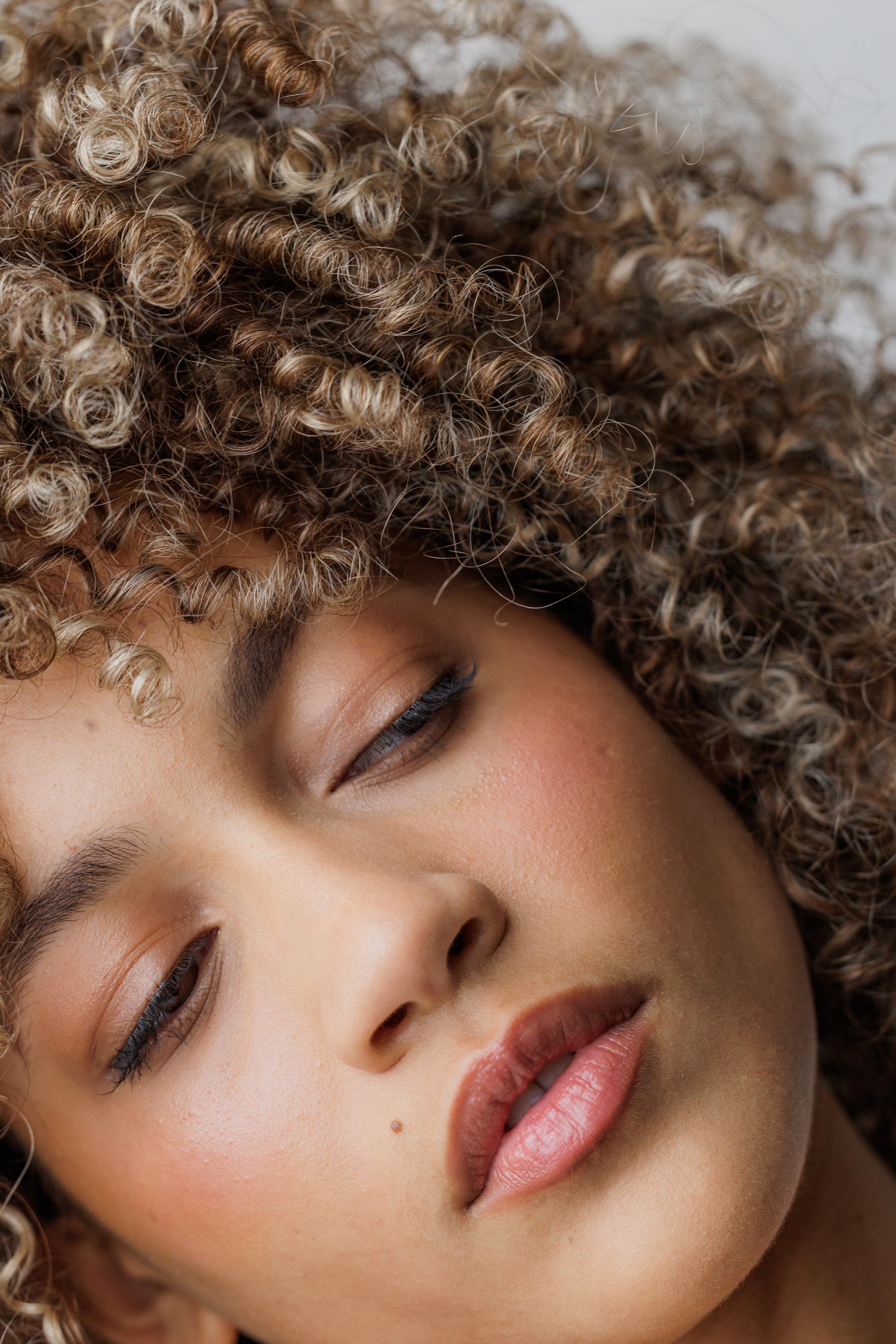 Close-up of a person with curly hair and closed eyes
