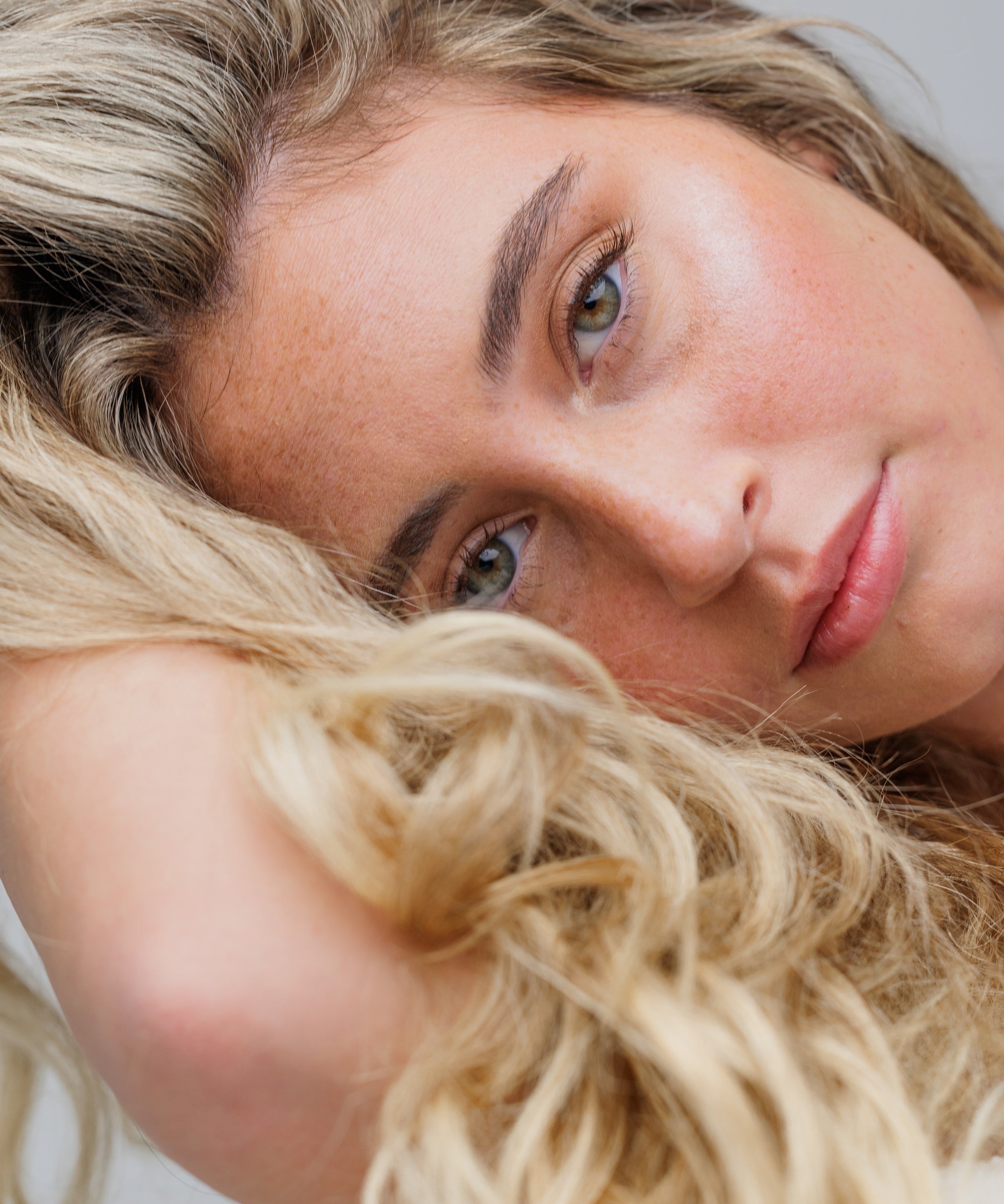 Close-up of a woman with blonde hair and blue eyes on a neutral background