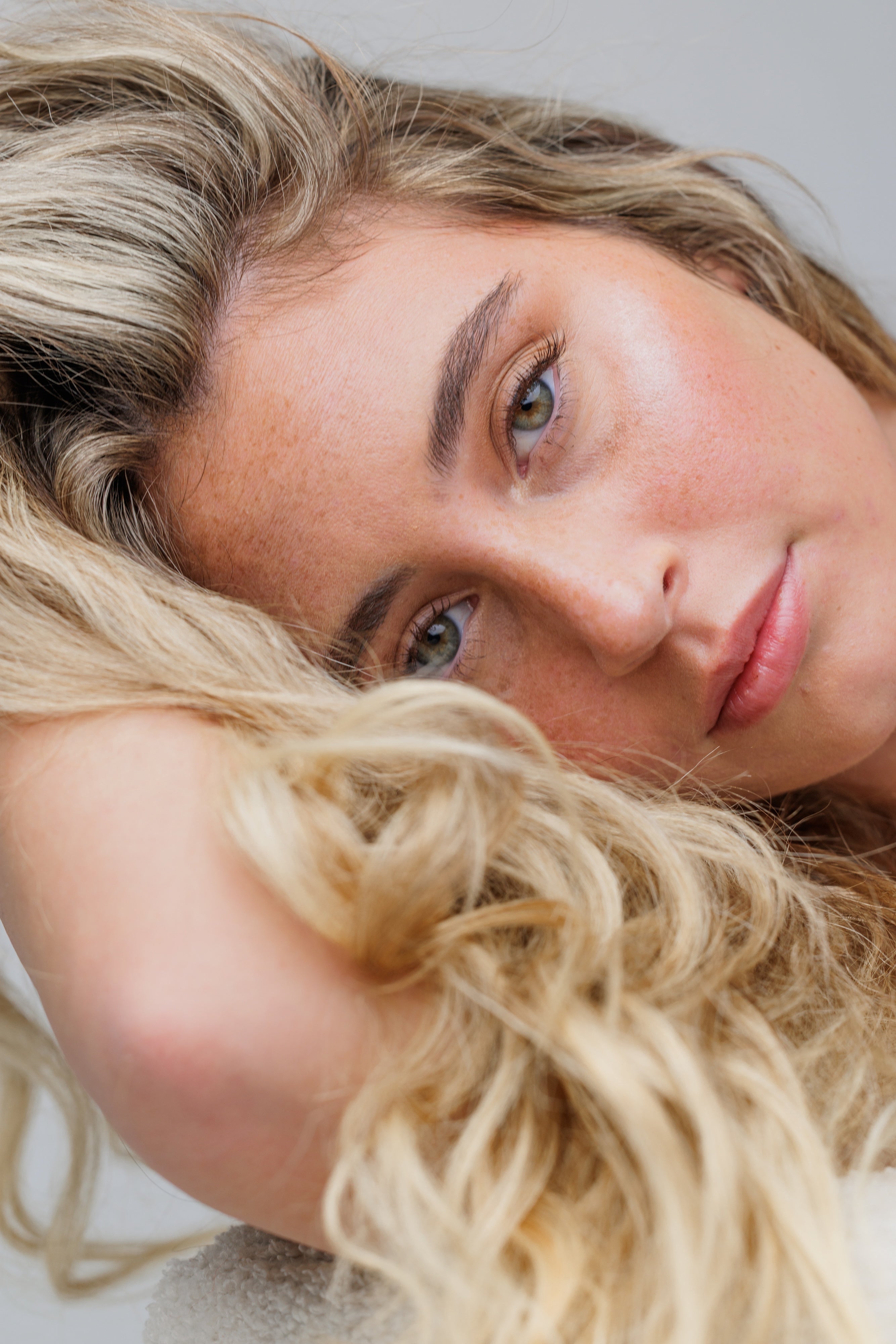 Close-up of a woman with blonde hair and blue eyes on a neutral background
