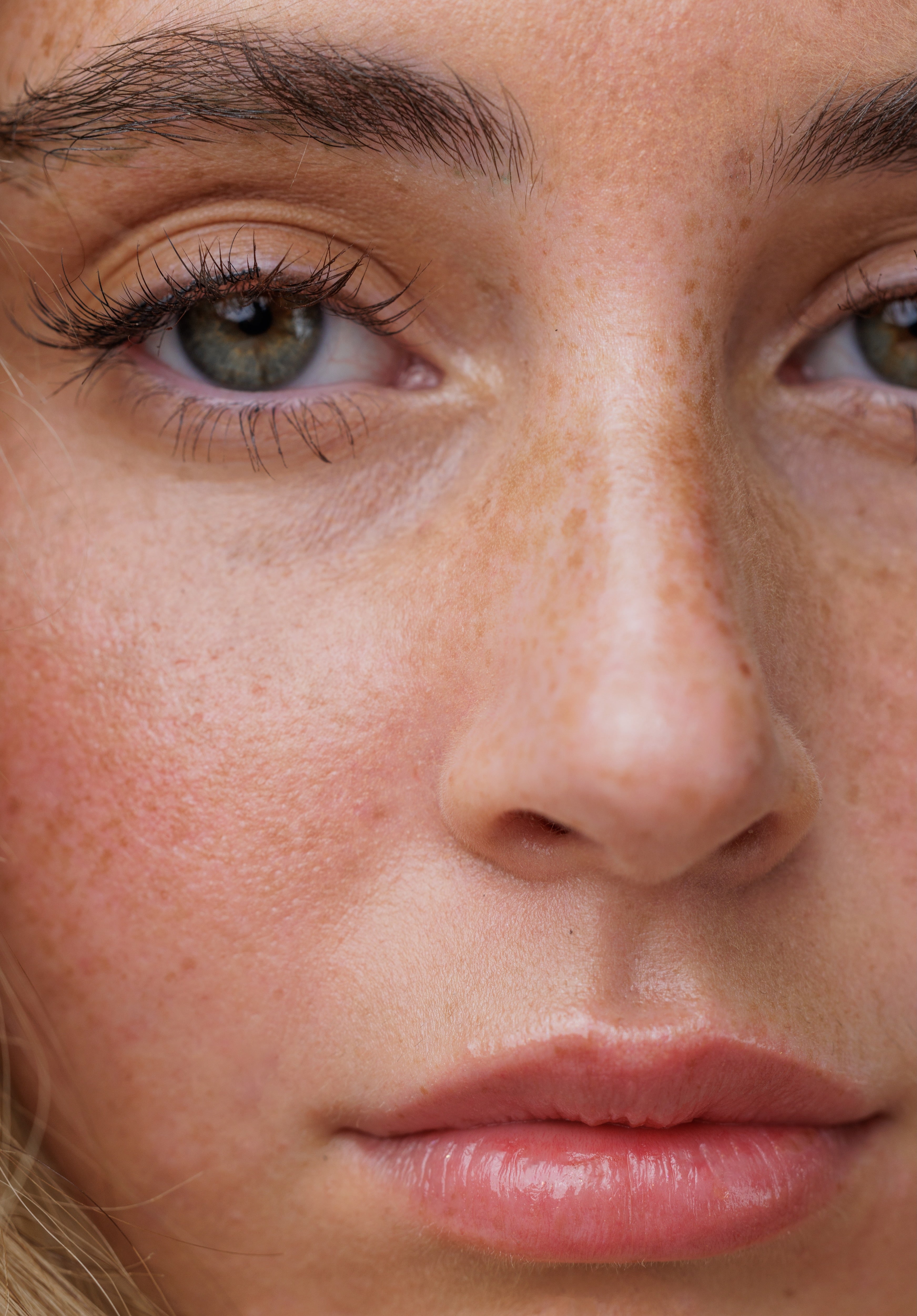 Close-up of a person's face with visible freckles and eye makeup.