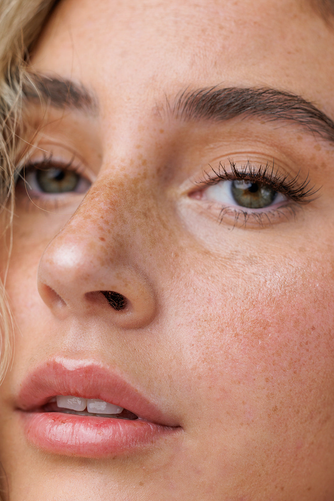 Close-up of a woman's face with freckles and green eyes.