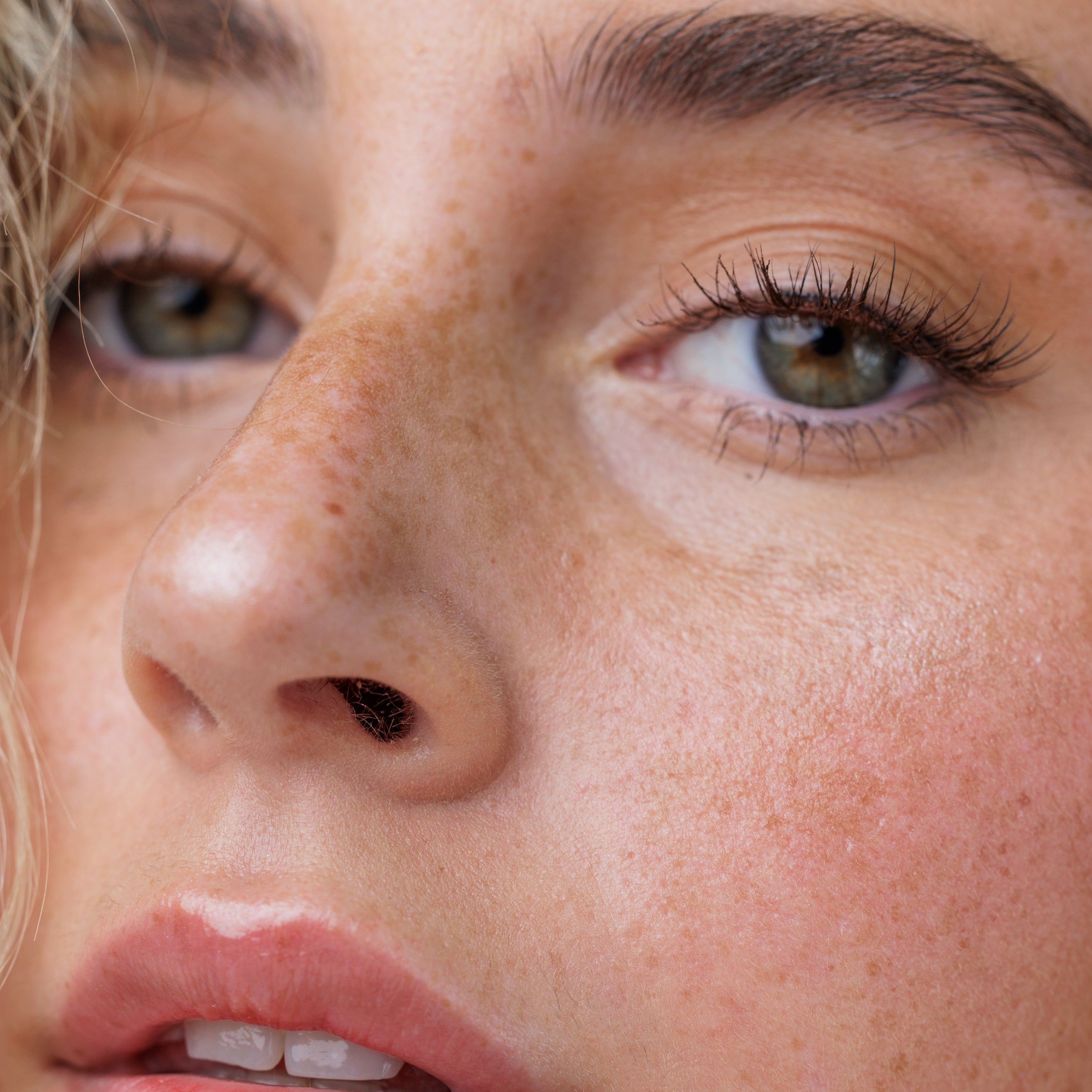 Close-up of a woman's face with freckles and green eyes.