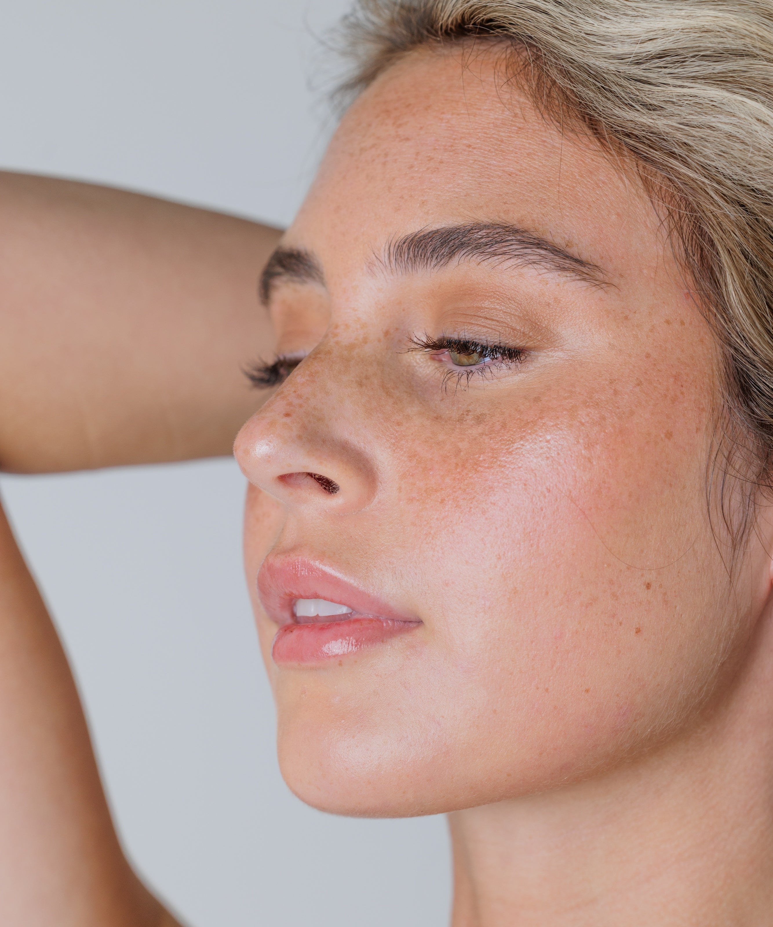 Close-up of a woman with freckles on her face against a plain background