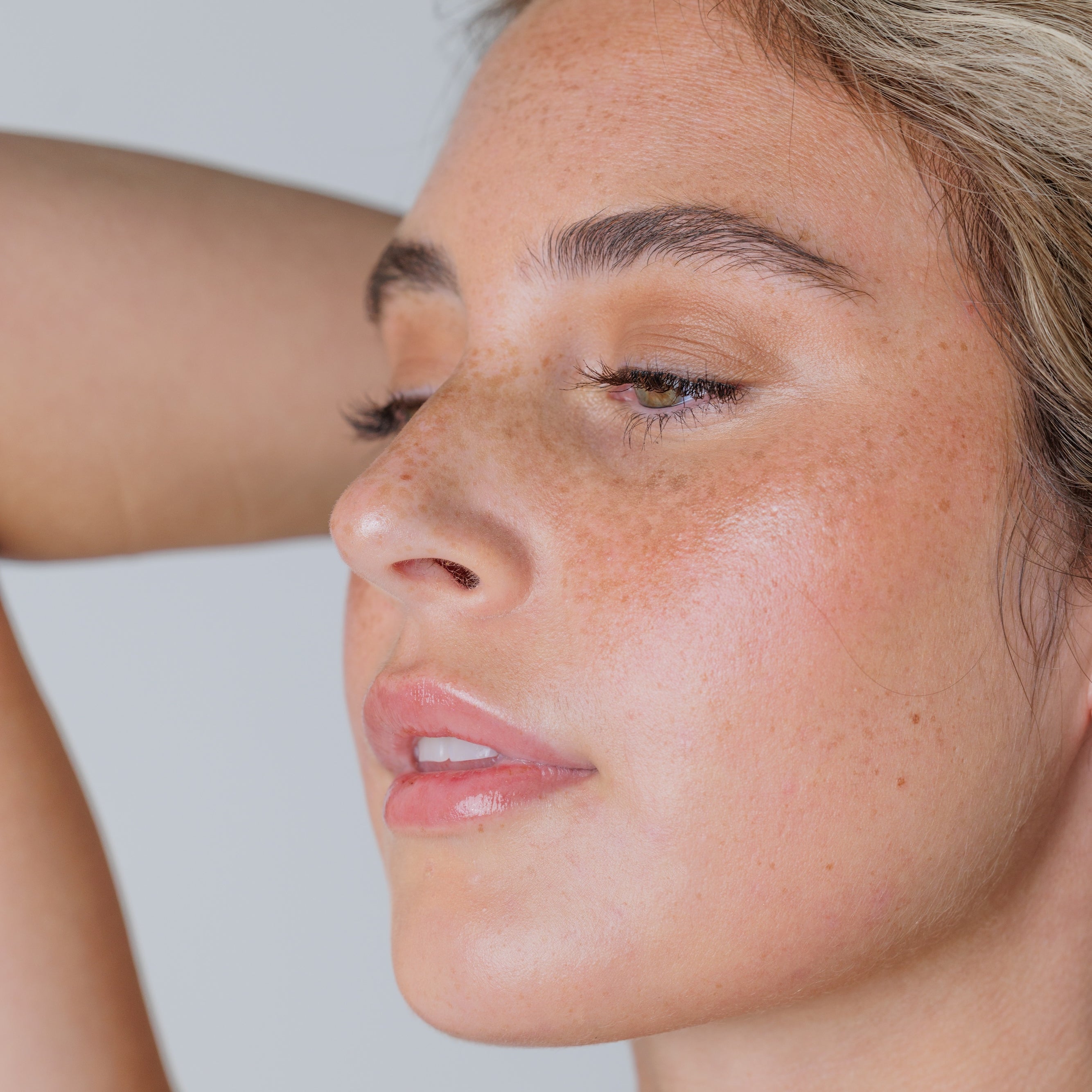 Close-up of a woman with freckles on her face against a plain background