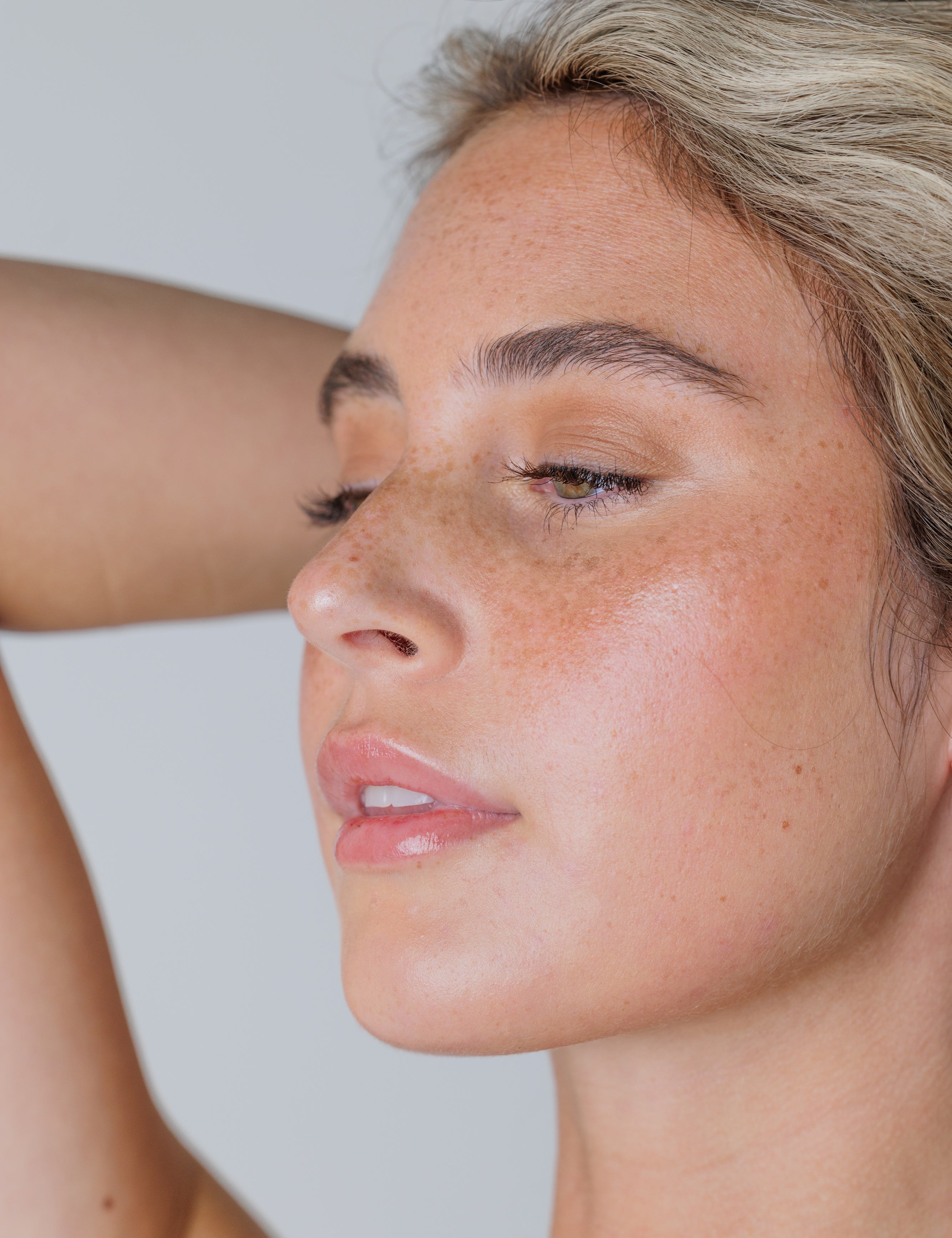 Close-up of a woman with freckles on her face against a plain background